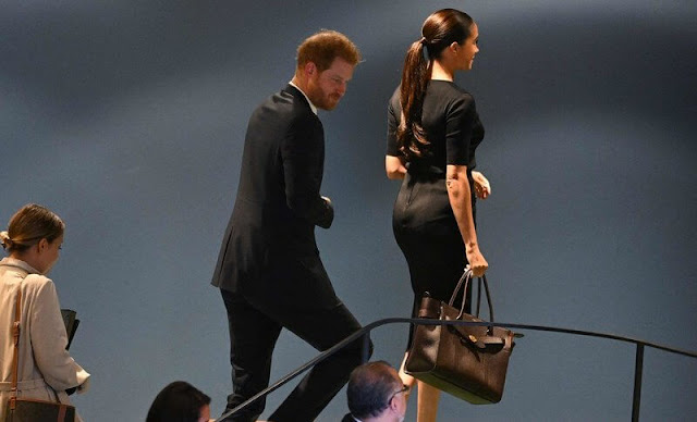 Meghan Markle wore a black knit gold button pencil skirt by Givenchy. Mulberry leather bag. Manolo Blahnik suede pumps