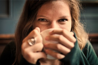 暖かい飲み物を飲んで笑みがこぼれる女性の写真