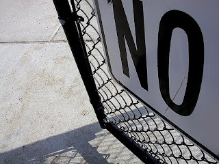 sign on chain link fence says No