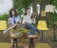 two people sit in a faux waiting room in a park
