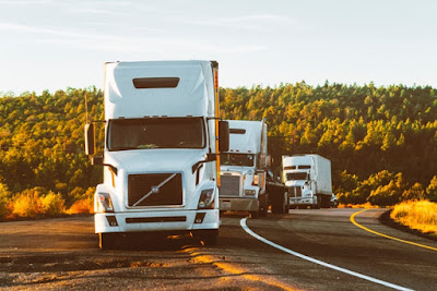 Three large white trucks parked by the road