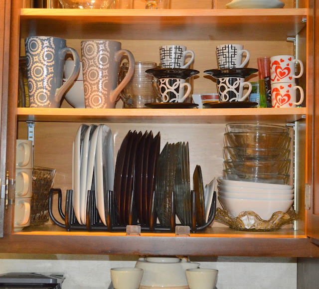 using a dish drainer to hold the dishes up right in a cabinet