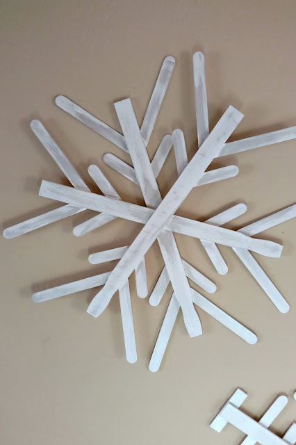 Use paint sticks from a hardware store and some paint to make these fun and rustic snowflakes for your home!  I made 3 of them for less than $4!