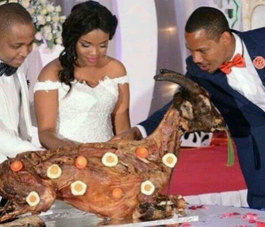 couples cut goat as wedding cake