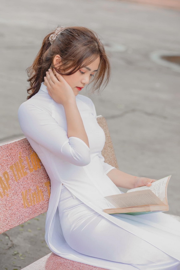Nữ sinh ngồi băng đá đọc sách