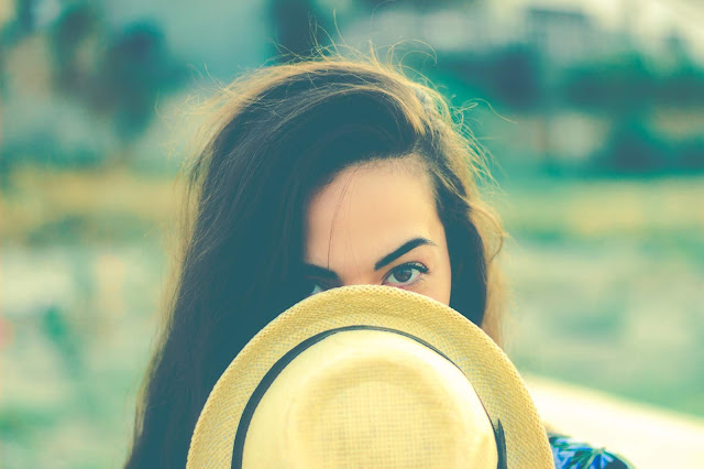 shy girl hiding behind hat