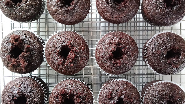 cored and baked gluten free chocolate cupcakes on a wire rack