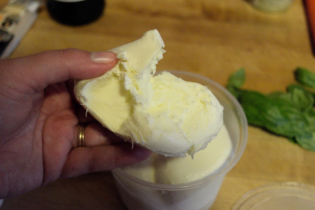 A ball of fresh mozzarella being torn apart.  