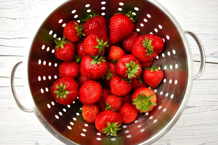 a colander full of strawberries