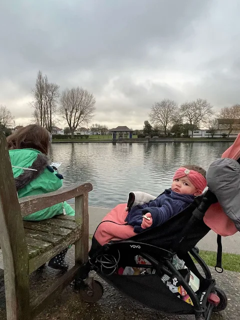 A baby looking at the camera looking confused in front of a duck pond in Southchurch Park