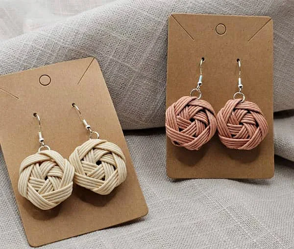 two pairs of neutral color woven paper earrings with silver ear wires on backing cards