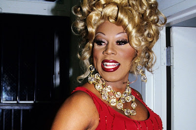 RuPaul landscape photo from the shoulders up wearing a red dress and jewels