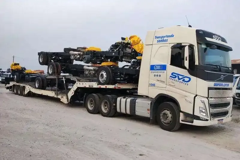 Volvo FH com carreta prancha carregada de chassis de ônibus