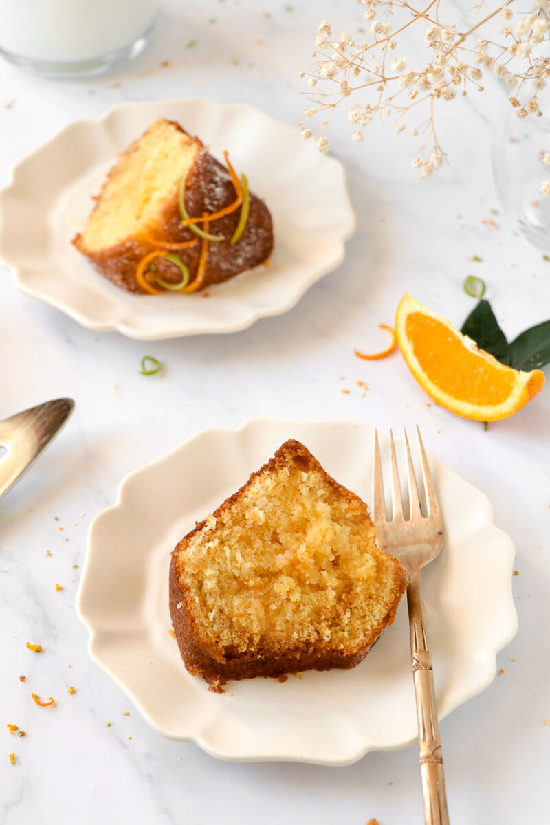 Slices of rum cake on white plates with gold forks.