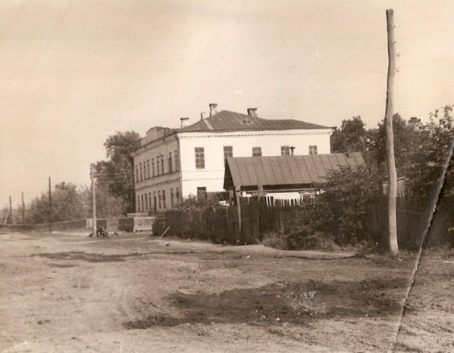 Старая фотография двухэтажного кирпичного здания на сельской улице