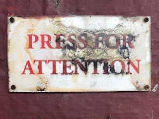 A photo of a sign in the guardhouse from when it served as the concierge's office for Fort House.  It reads 'Press for Attention.' Photo by Kevin Nosferatu for the Skulferatu Project.