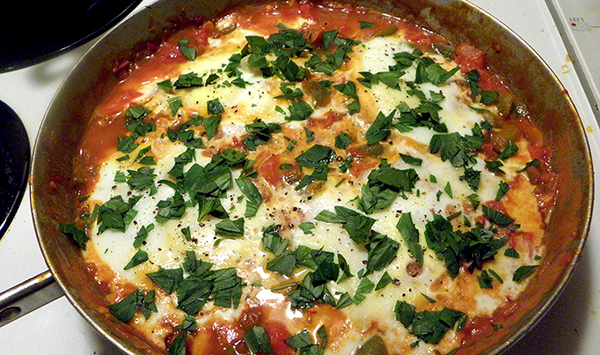 poached eggs and tomato sauce topped with parsley and pepper