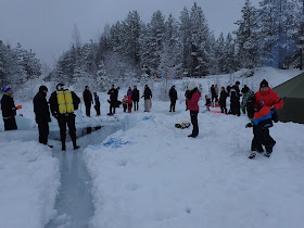Sukeltaja ja muita ihmisiä seuraa avannon ympärillä jäällä sukellustapahtumaa