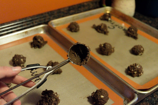 The triple chocolate macadamia nut cookie dough being scooped out onto the cookie sheet. 