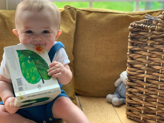 Baby facing to camera, smiling and chewing a book