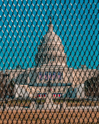 color photograph of US Capitol behind fence after January 6 insurrection