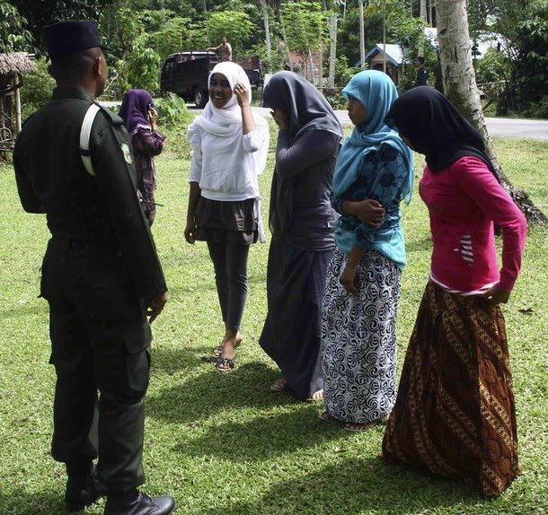 Sharia police give advice to women caught wearing tight pants during a 