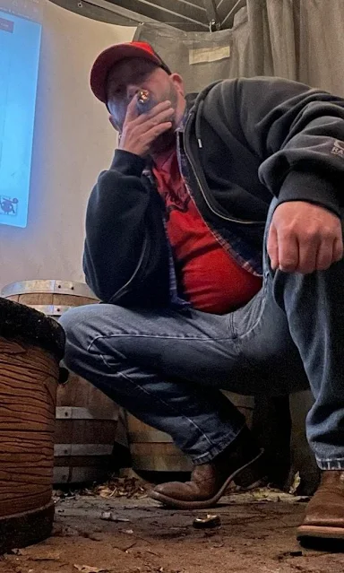 C 1/2 bearded daddy takes puff of stogie kneeling in cowboy boots