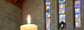 A candle lighting up a stained glass window