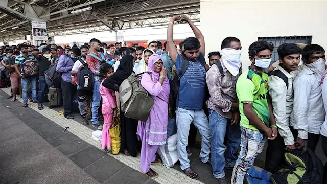 Image Attribute: Migrant workers and their families queue to board a train at Mumbai railway station after government-imposed restrictions on public gatherings in attempts to prevent the spread of COVID-19 / Source: Prashant Waydande/Reuters