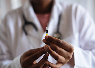 photo of a vaccine needle being handled by a health care provider.