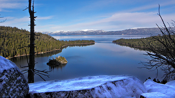 Overlooking Emerald bay from snowy rocks with mountains in distance