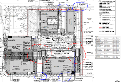 Site plan drawing showing multiple buildings and parks on a half city block with a dog-leg roadway through the site. The intersection of the roadways with the sidewalk are circled in blue and pedestrian areas within the site are circled in red.