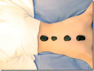   	spa: a girl takes a hot stones massage