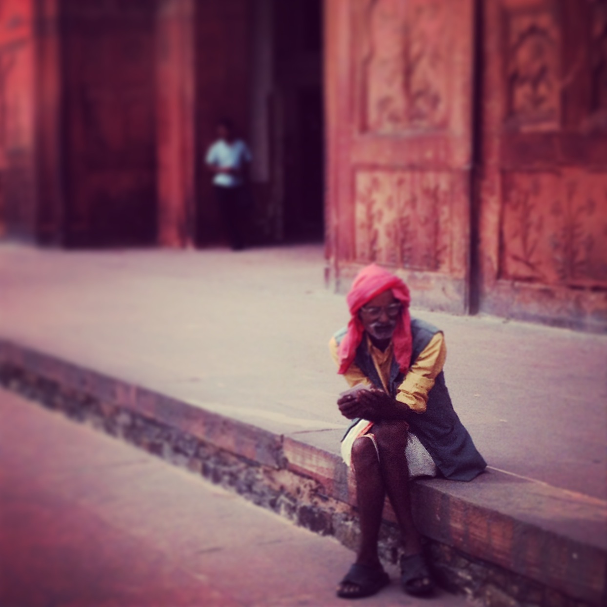 indian man wearing pink turban sitting on a step in delhi, India