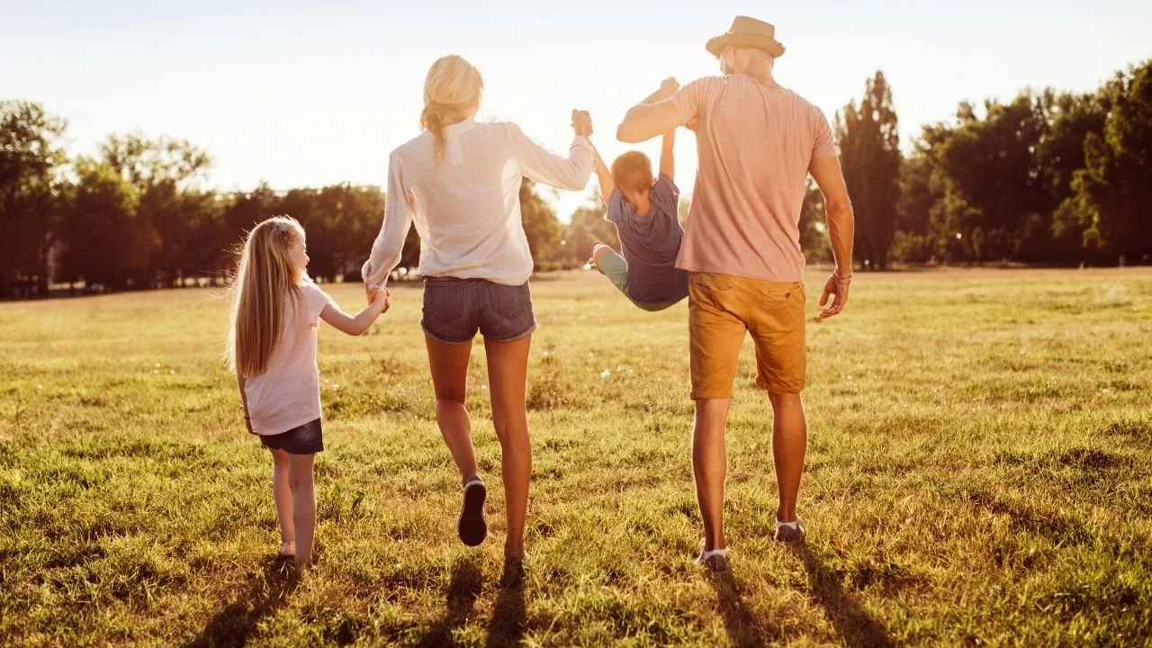 Children having fun with parents walking in a beautiful park at summer.