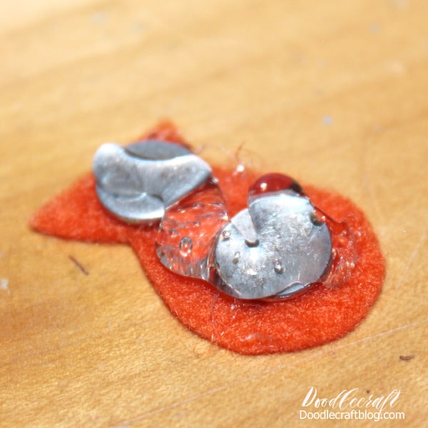 Next, hot glue a washer or metal disc or 2 onto one of the felt fishes.   Then add hot glue to the top of the washers, around the edge of the felt.