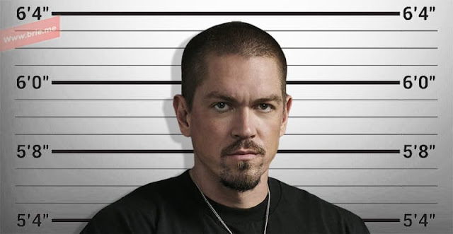 Steve Howey posing in front of a height chart background