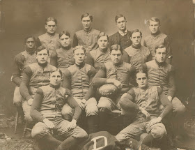 A photograph showing a group of men seated for a football team portrait.