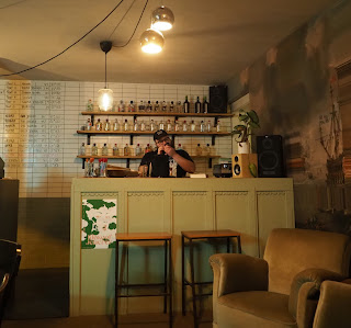 A man in a baseball cap stands behind a bar preparing drinks