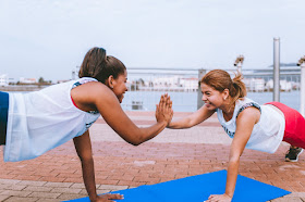 Two ladies touch their hands while they exercise