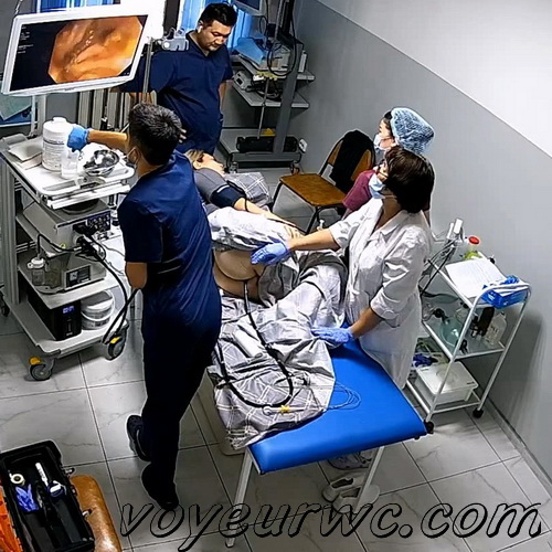 A patient lies on their side while a gastroenterologist inserts a colonoscope (Female colonoscopy SpyCam 24)