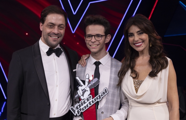 Na foto, o vencedor da Season 11 do The Voice Portugal, José Bacelar, emociona a plateia com sua poderosa voz. Ao seu lado, o mentor António Zambujo, com uma expressão de orgulho, saboreia a vitória conquistada. A apresentadora do programa, Catarina Furtado, transmite entusiasmo e felicidade pelo talento revelado nesta edição das Provas Cegas. Uma equipe apaixonada pela música, pronta para celebrar o sucesso dos participantes e oferecer uma experiência única ao público.