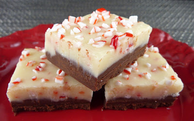 Three pieces of Peppermint Bark Fudge: a dark chocolate bottom layer topped with a white peppermint layer. Photographed on a red plate.