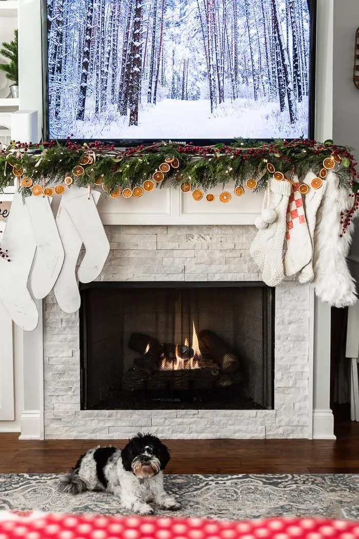 Christmas mantel with white stockings, dried orange slice garland, fire, pup