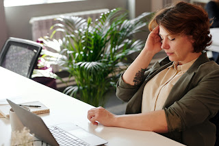a person sitting at a desk holding their head | Chiropractic Ann Arbor