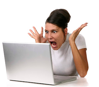 a woman with shocked expression staring at a laptop