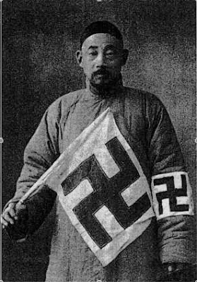 Chinese man wearing a swastika armband and holding a large flag with a swastika.