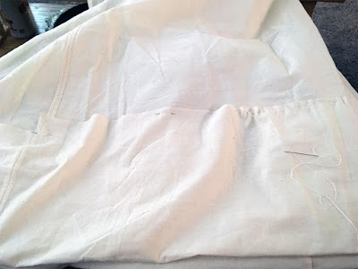 A tremendously dep hem pinned up in white muslin, with a few telltale wrinkles.