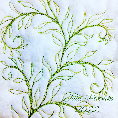 A free motion quilting design of flowing green ferns