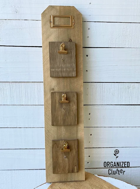 Photo of stained fence board with 3 mini clipboards and a metal tag frame